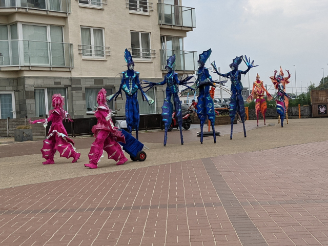 Performers dressed as sealife walking down the beach front on stilts